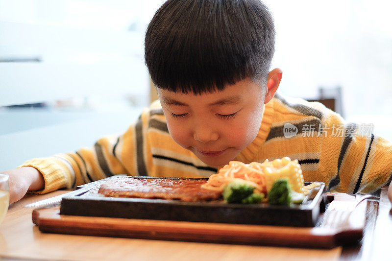 亚洲男孩在餐厅吃牛排