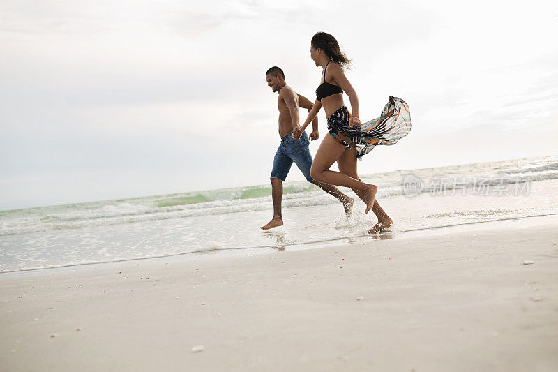 在沙滩上跑步时牵手的恩爱夫妻