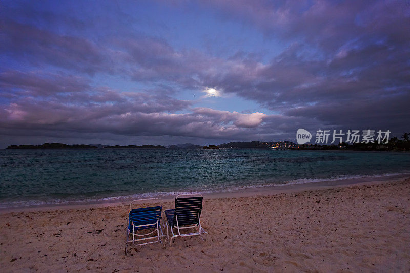月光照耀的海滩上的两把椅子