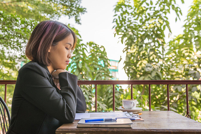 穿黑西装的女人低头看桌子上的文件