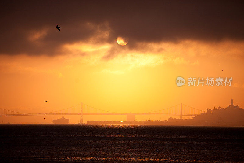 日出在旧金山与海湾大桥和货轮。