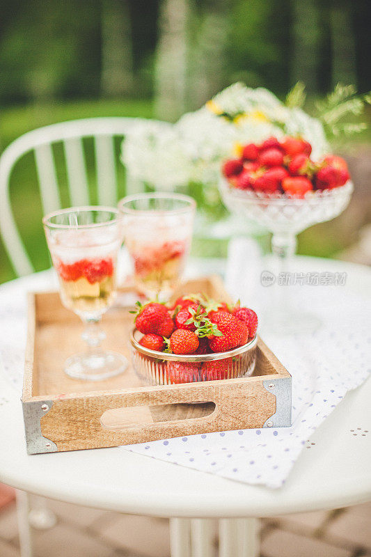 夏天的草莓和鸡尾酒在花园里的桌子上