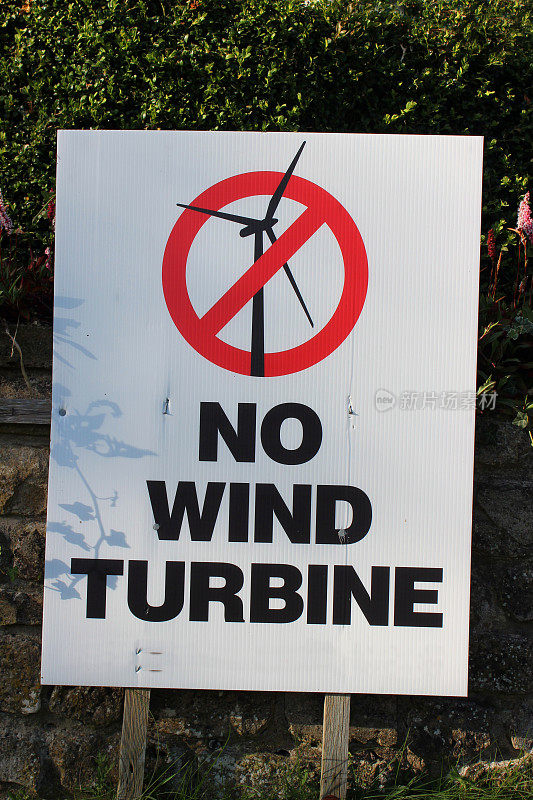路边标牌上写着“无风力涡轮机”，可替代能源