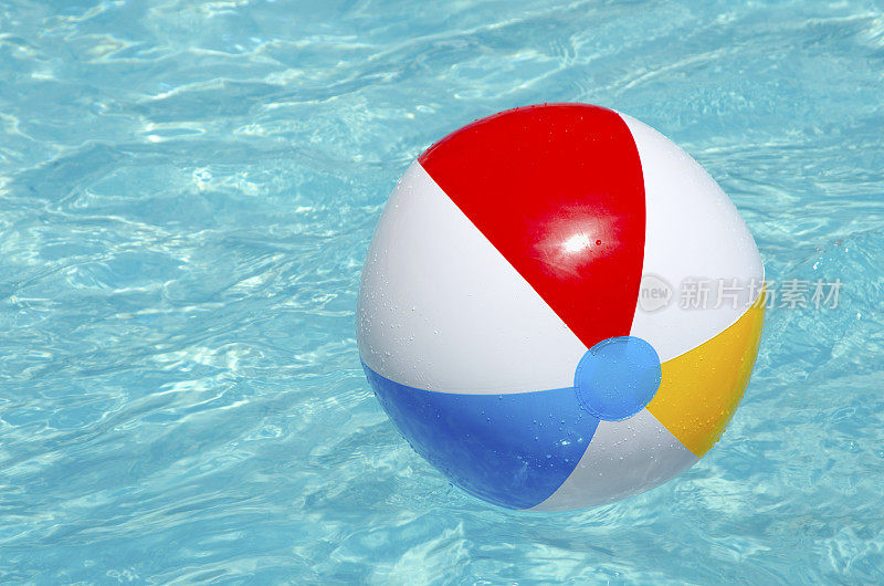 五颜六色的沙滩球漂浮在游泳池里。