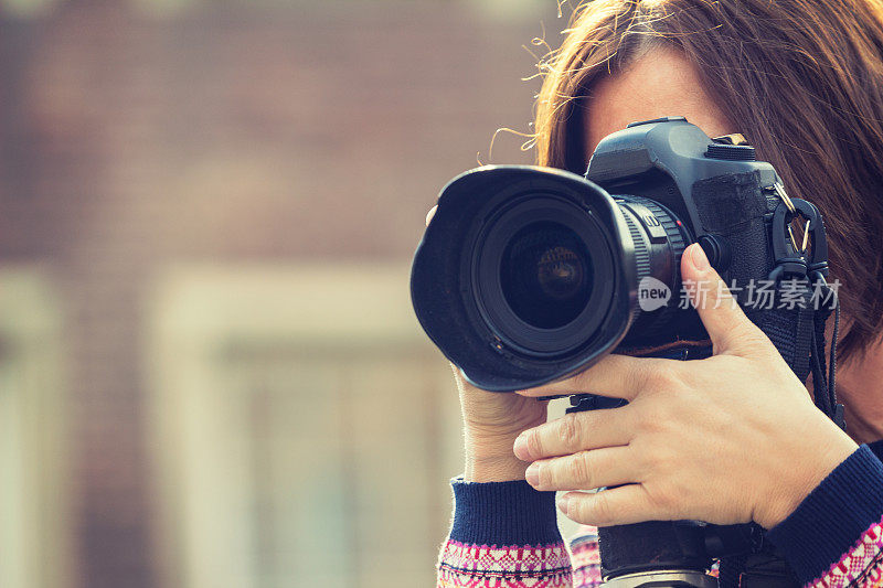 女性摄影师使用单反相机拍照