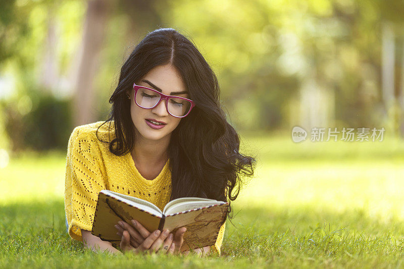 年轻女子在绿草地上看书