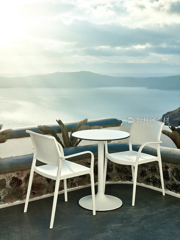 两张椅子和一张小桌子，在美丽的露台上可以看到希腊圣托里尼的美丽海景