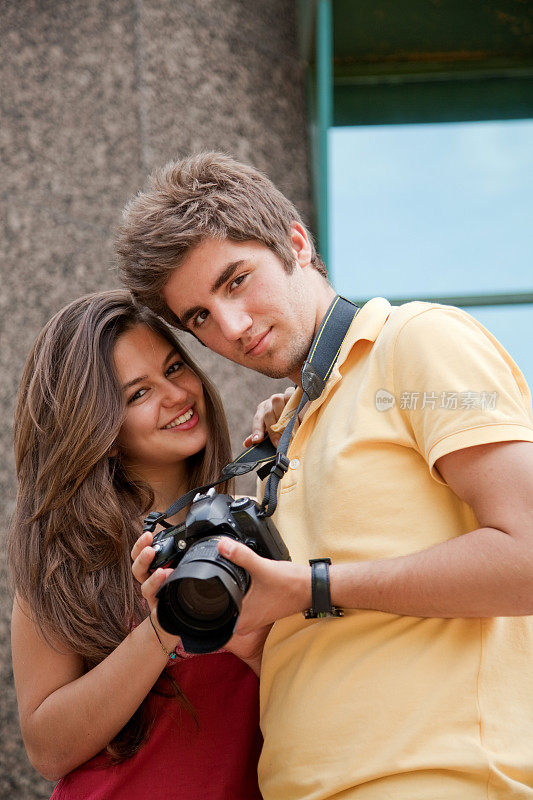一对快乐的年轻夫妇看着他们的相机