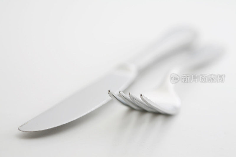银色的刀叉放在白色的背景上