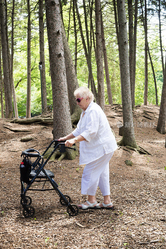 老妇人推着步行者穿过森林