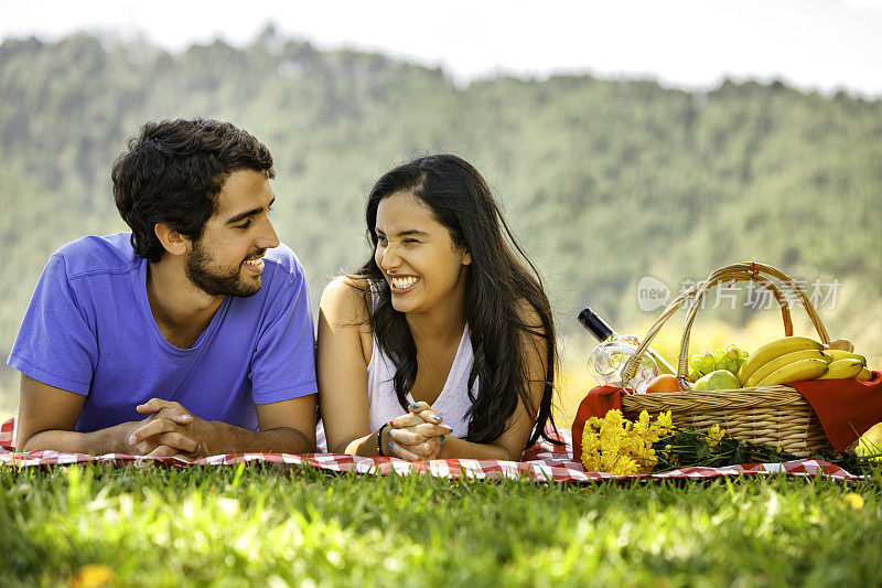 轻松和热爱拉丁幸福夫妇享受野餐在公园