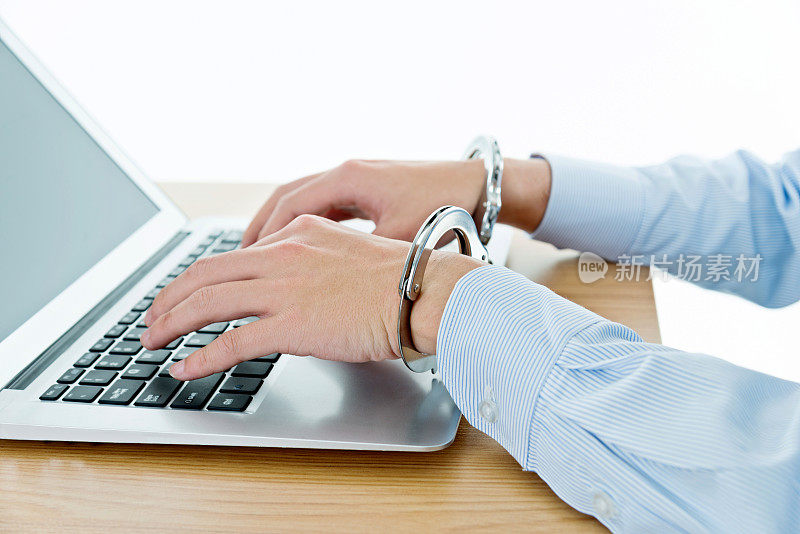 商人双手被手铐绑在笔记本电脑键盘上