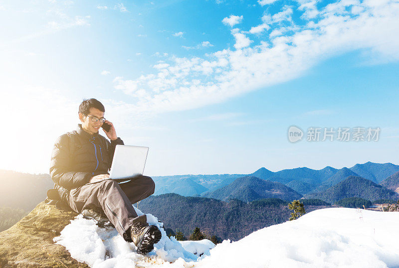 在山里用手提电脑和手机的男人