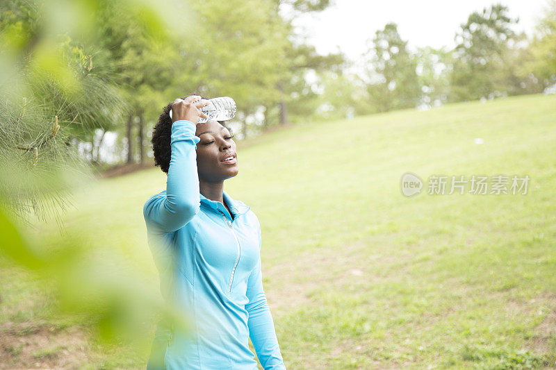 一位非洲裔妇女在附近的公园喝水休息。