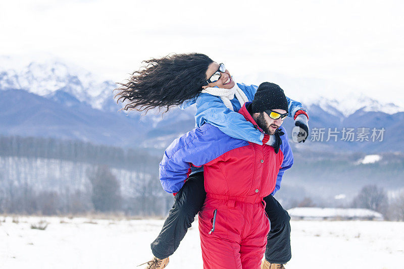 好玩的年轻夫妇在雪地里骑马