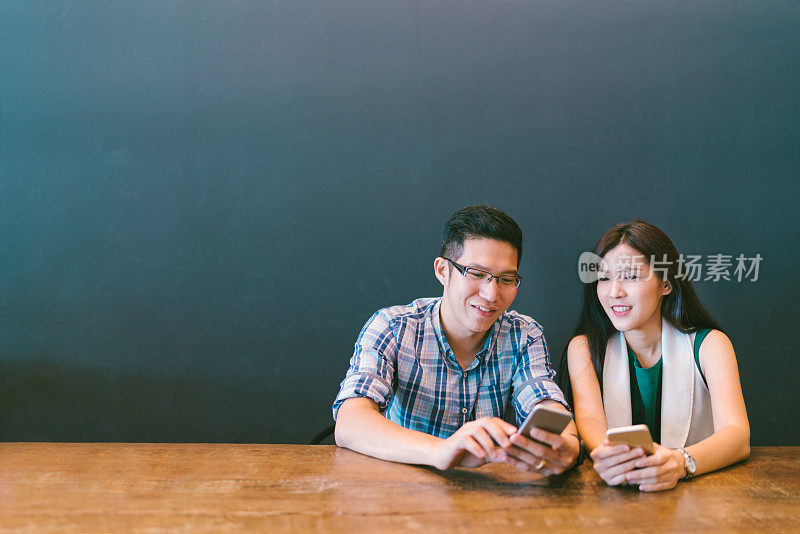 年轻的亚洲情侣，大学生，或同事一起在咖啡馆使用智能手机，现代生活方式与电子产品技术或爱情和关系概念，与复制空间