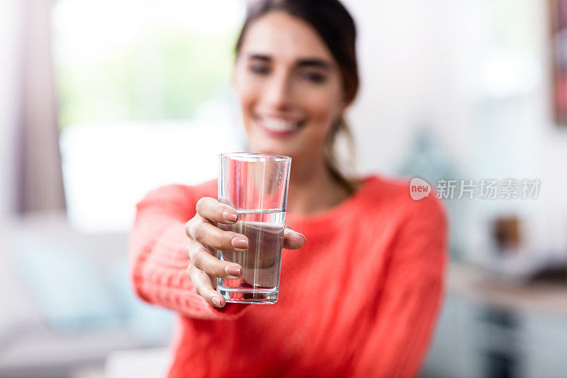 一名年轻女子展示了装有水的水杯