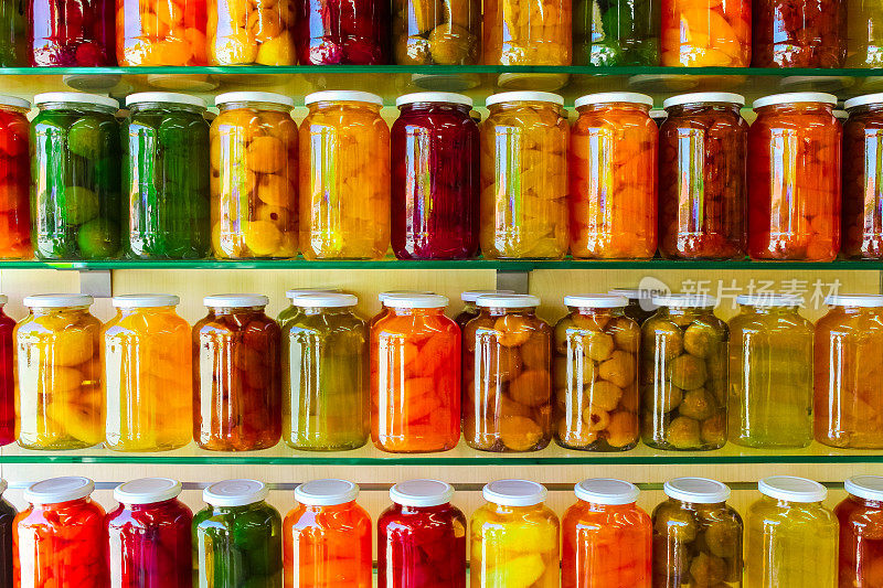 各种各样的罐装水果和蔬菜果酱放在玻璃架子上