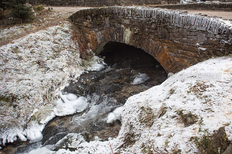 一座古老的桥横跨一条冰冻的小溪。
