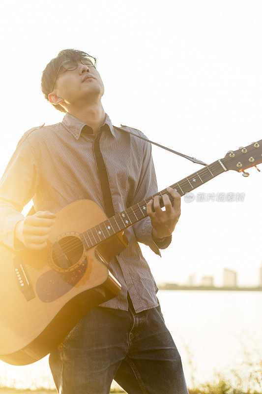年轻男子在夕阳下弹奏吉他