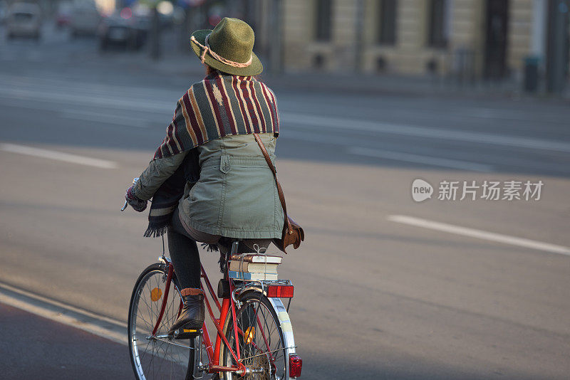 在市中心骑着老式自行车的女人的后视图