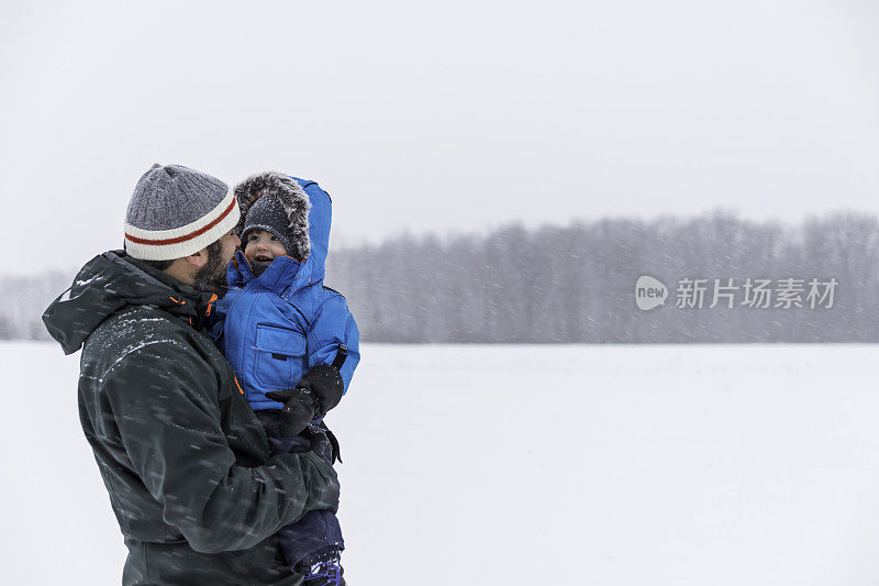 父亲和儿子在户外玩冬天森林暴风雪