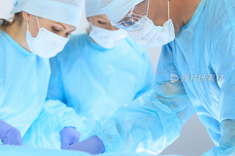 医疗队进行手术三个外科医生在忙着照顾病人。医学，兽医或医疗保健和医院急诊