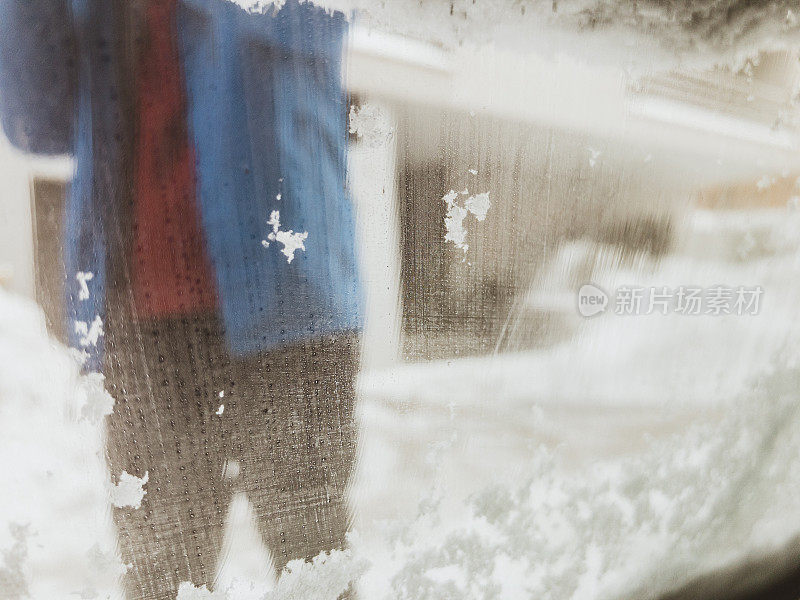 冬天的场景，成熟的男人在清理车上的积雪。用手机拍的照片。