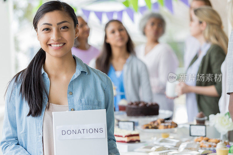 年轻美丽的西班牙裔女子在烘烤义卖期间募集捐款