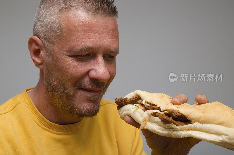 饥饿的大人捧着炸肉排中的小圆面包，准备吃