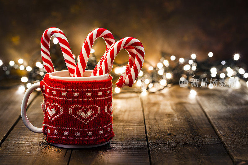 圣诞背景:木桌上放着一只马克杯里的拐杖糖