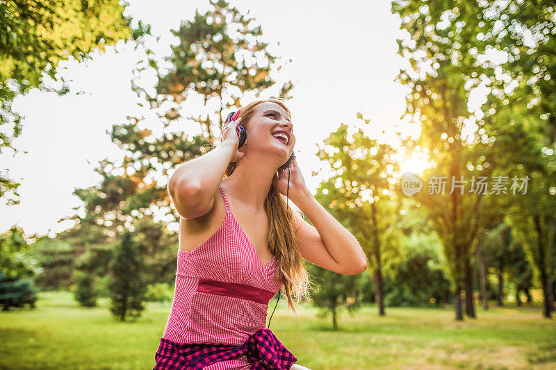 年轻女孩在城市公园里听音乐