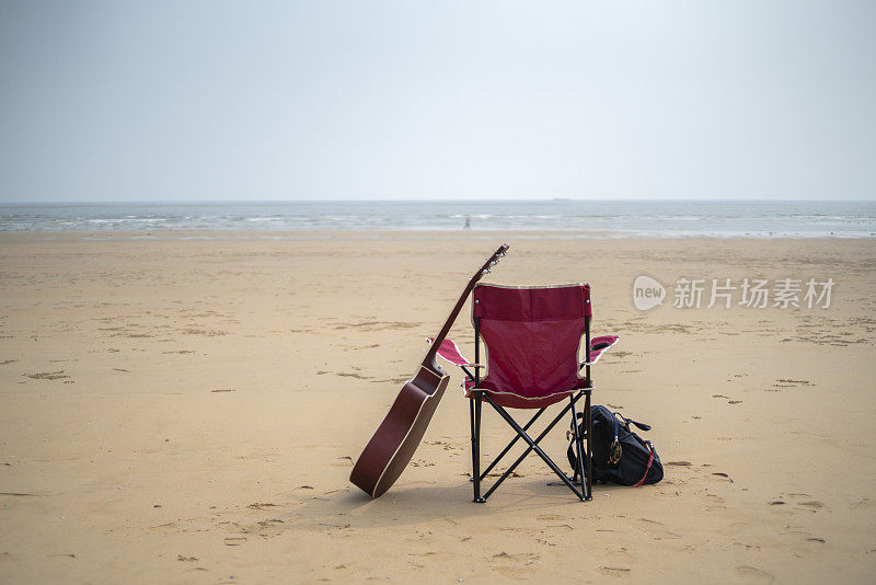 吉他，背包和沙滩上的露营椅