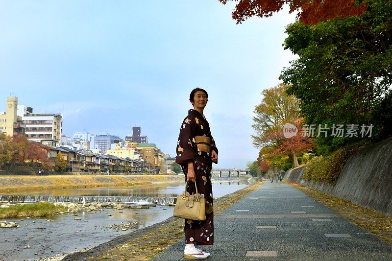 穿着和服的日本妇女在京都的秋天沿着加茂河行走