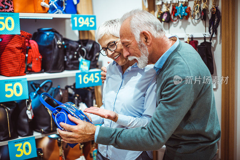 一对老年夫妇在一家手提包和饰品店一起寻找一个蓝色的小手提包