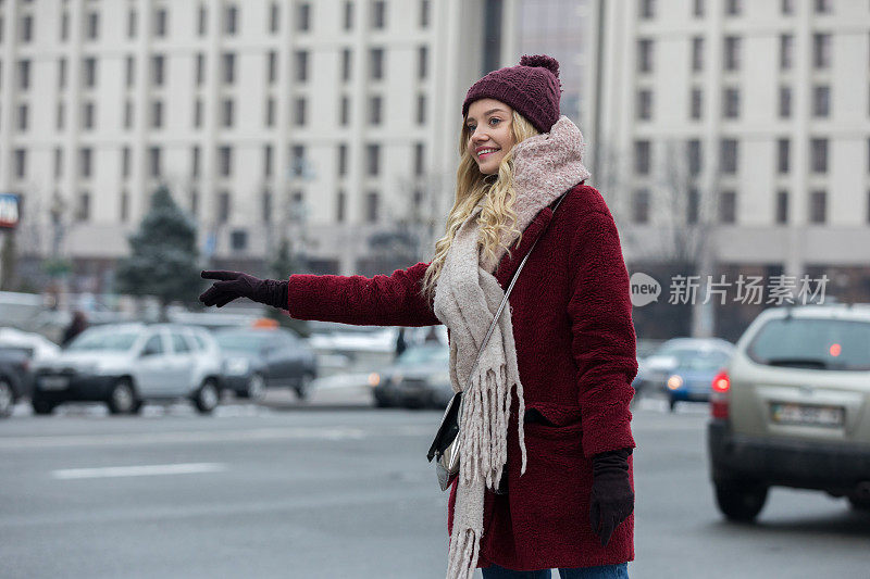 一个年轻女子站在大街上叫出租车