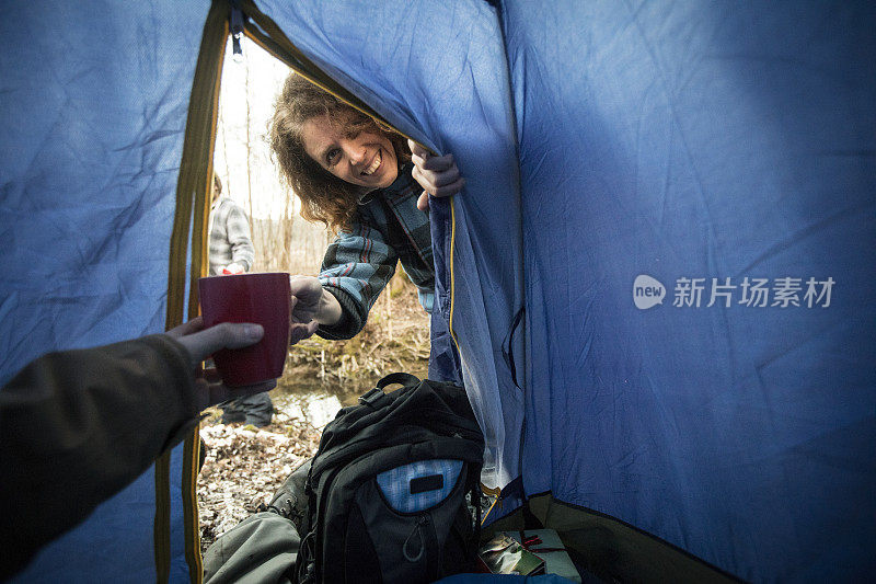 微笑的中年妇女把咖啡杯给一个在帐篷里的男人