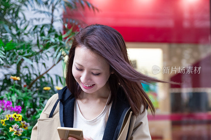 一个日本女人在街上看智能手机