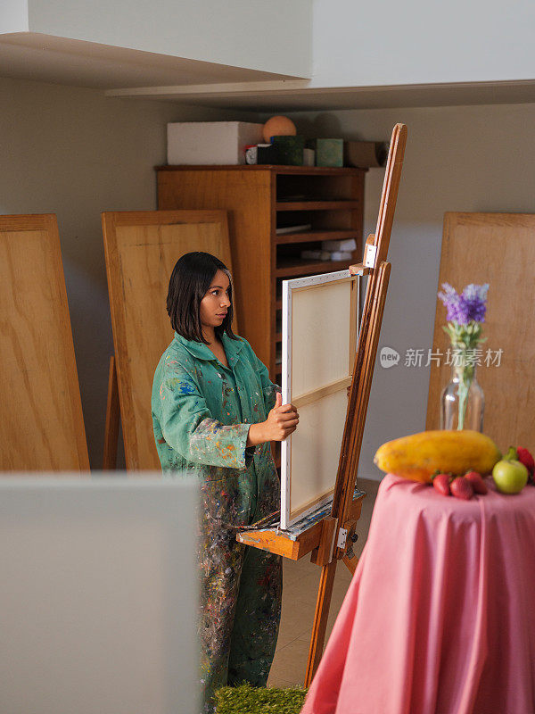 一个女艺术学生正在把画布放在画架上