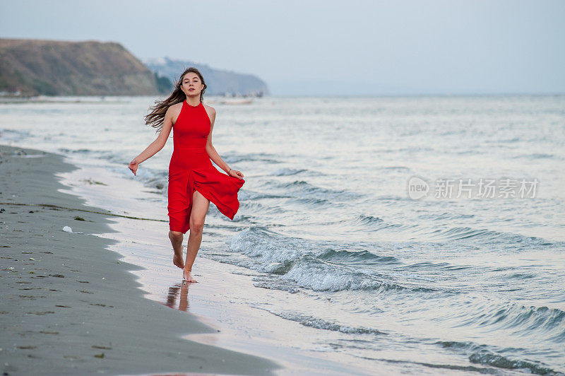 穿红衣服的年轻女子在海滩上跑步