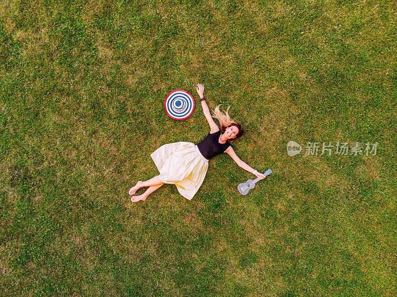 快乐的年轻女子躺在草地上