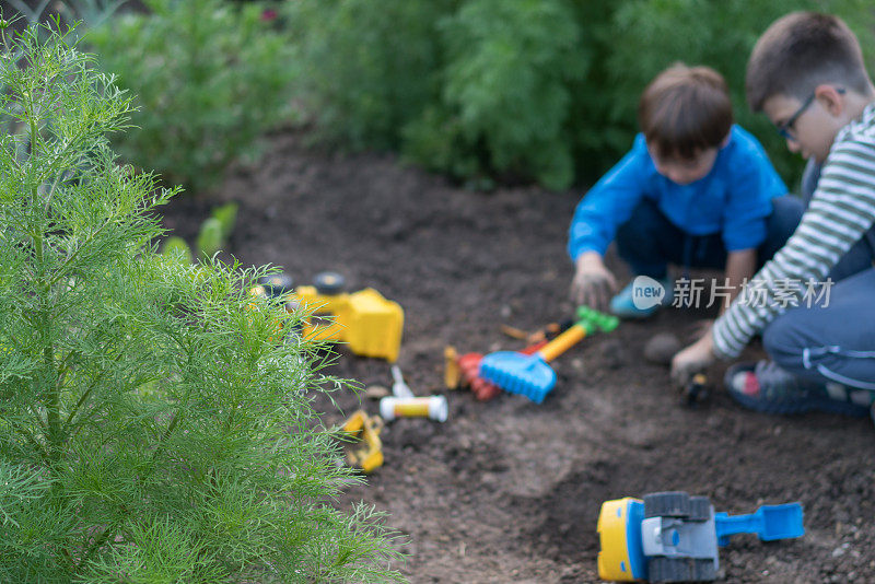 小弟弟们在泥地里玩他的玩具卡车