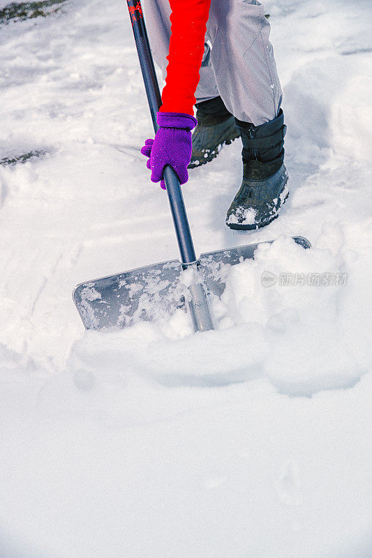 老妇人正在用雪铲清理积雪