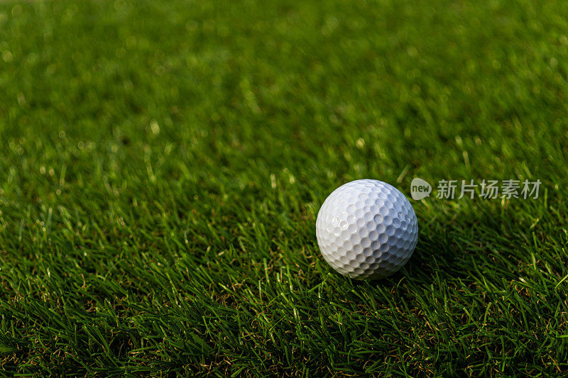 高尔夫球在绿色，绿色的草与高尔夫球近距离在柔和的焦点在阳光。运动操场为高尔夫俱乐部的概念-广泛的景观为背景的字母高尔夫球打。