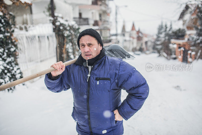 一位老人正在扫雪