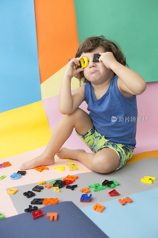 可爱的小男孩玩着五颜六色的字母