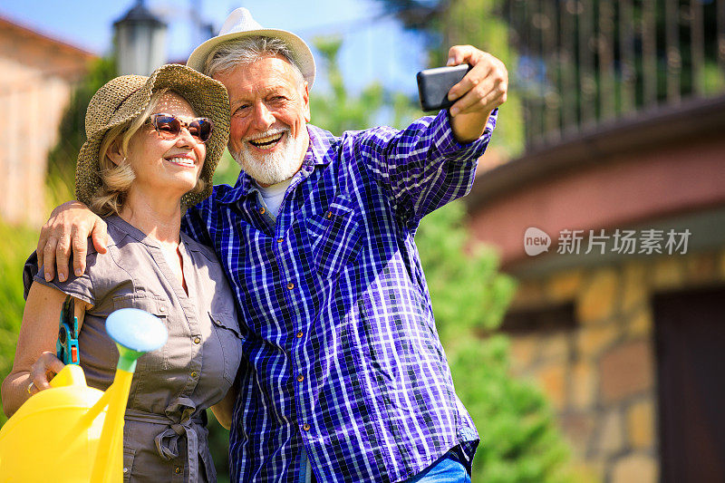 一对老年夫妇在一个阳光明媚的日子里用手机自拍