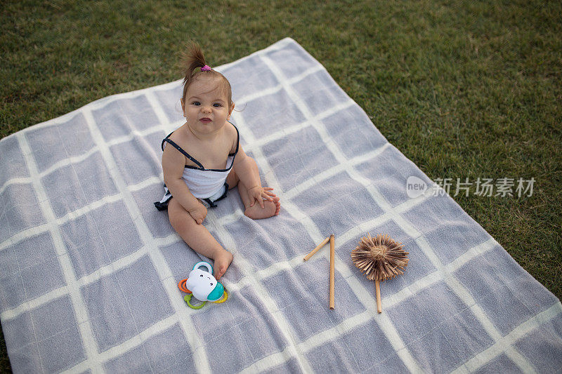 10个月大的女婴坐在公园的毯子上