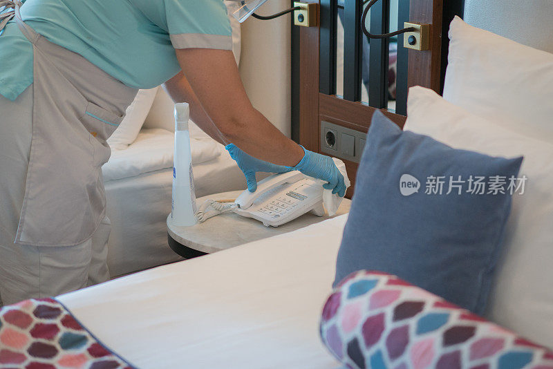 客房服务员用抗菌湿巾擦拭酒店房间里的手机