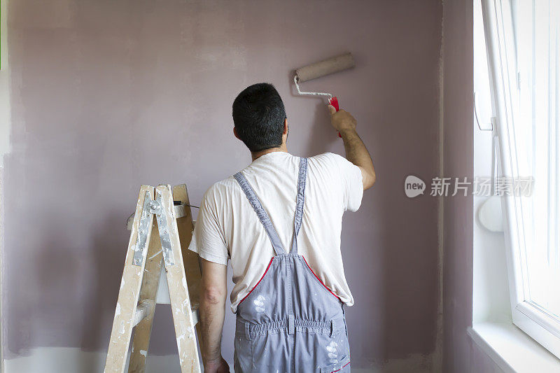 专业油漆工用滚轴在墙上作画